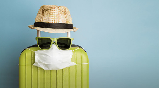 Koffer mit Sonnenbrille, Hut und Maske